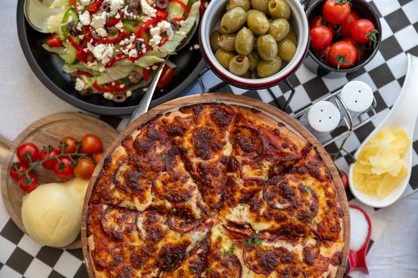The full Paradise spread — pasta bowls beside the pies