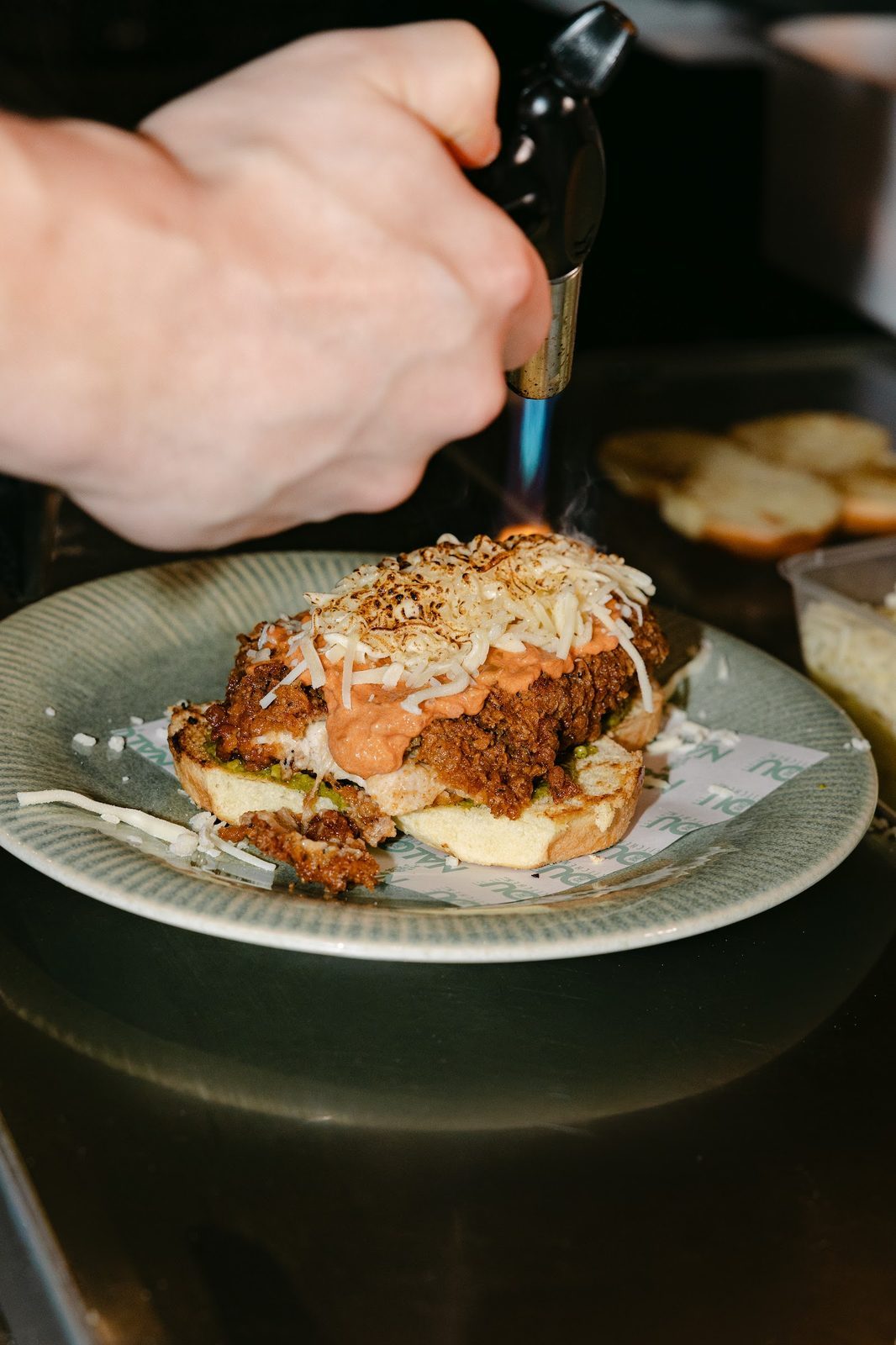Nalou Kitchen fried-chicken sandwich being blowtorched