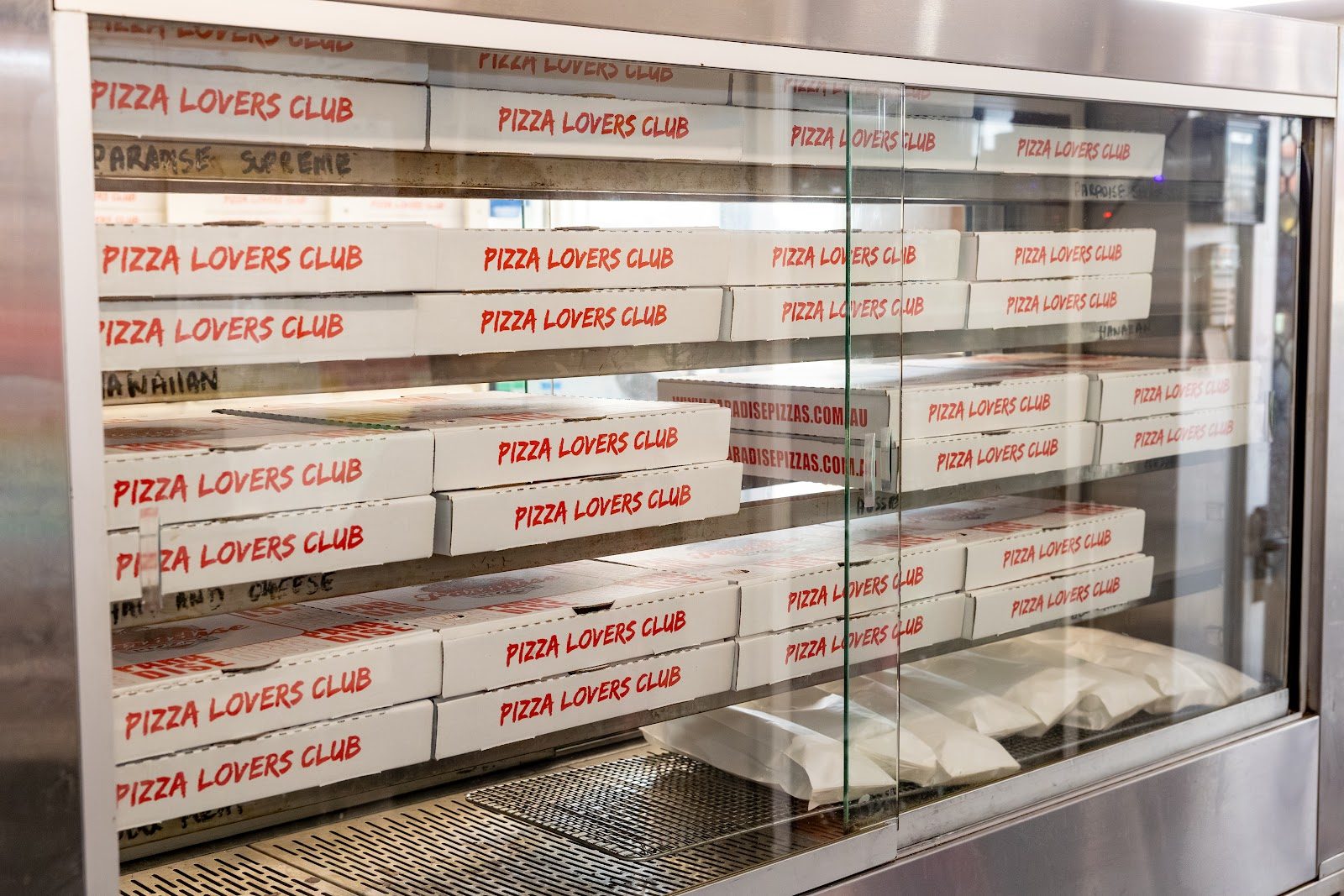 Paradise Pizzas ham-and-cheese and Hawaiian pies boxed in the warmer, PIZZA LOVERS CLUB