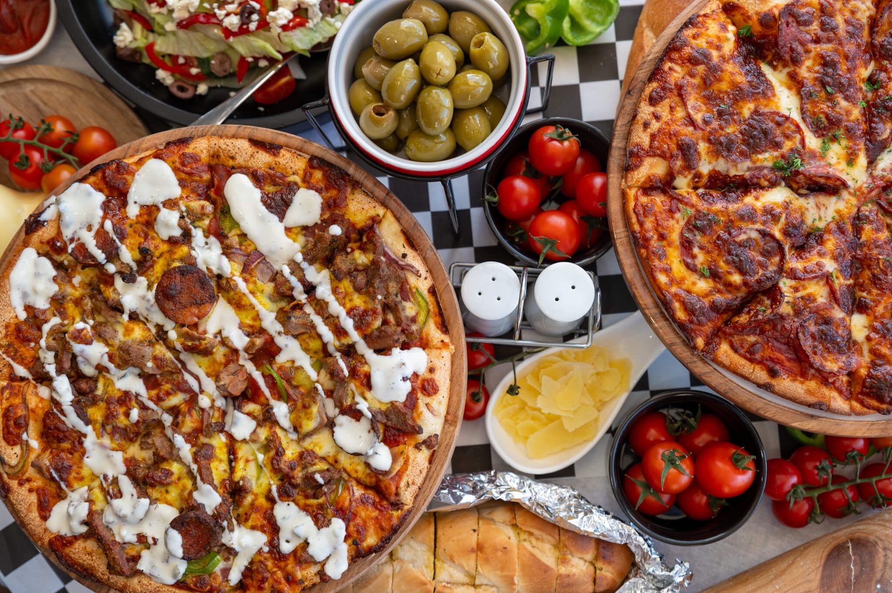 Paradise Pizzas feast — loaded pies on the checkered table